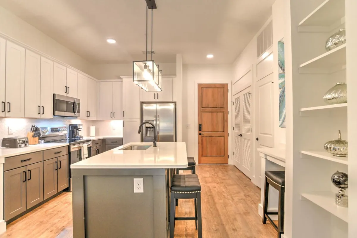 A bright, inviting kitchen featuring a spacious island, modern stainless steel appliances, and stylish open shelving. The setup is perfect for preparing morning coffee or whipping up a hearty breakfast, with ample counter space for culinary creativity. The lighting and arrangement create a warm, welcoming atmosphere ideal for daily rituals.